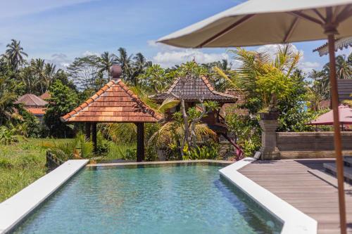 a swimming pool in a resort with an umbrella at Billys Ayodya Villa in Perean