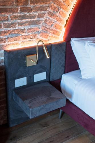 a bed with a nightstand next to a brick wall at Pavillon Suite in Peschiera del Garda