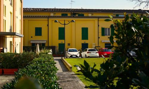 un bâtiment jaune avec des voitures garées dans un parking dans l'établissement Appartamento con parcheggio privato a Lucca, à Lucques