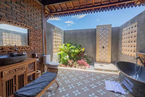 an outdoor bathroom with a tub and a sink at Billys Ayodya Villa in Perean