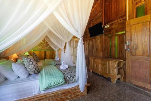 a bedroom with a bed with a canopy and a television at Billys Ayodya Villa in Perean