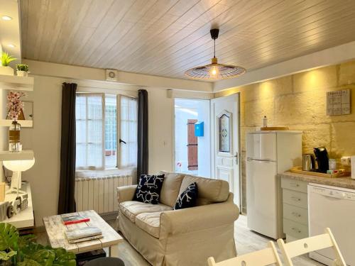 een woonkamer met een bank en een keuken bij Rare Maison au centre ville avec terrasse et clim Arles Camargue in Arles