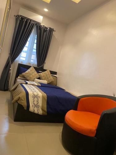 a bedroom with a bed and a orange chair at Hope Residence hotel and suite in Lagos