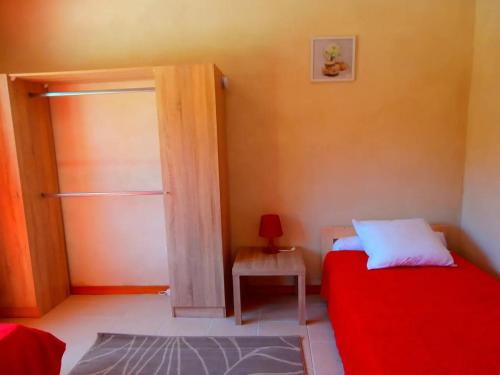 um quarto com uma cama vermelha e uma pequena mesa em La petite Palasse em Le Thor