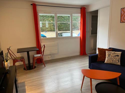 ein Wohnzimmer mit einem blauen Sofa und einem Tisch in der Unterkunft L'éclectique - Appartement 40m2 + Parking in Châteauroux