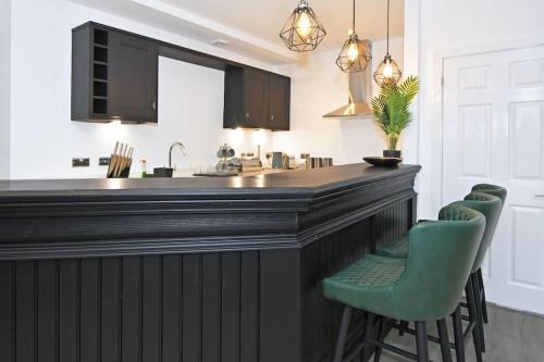 a kitchen with a large bar with green chairs at The Pub - By Sigma Stays in Crewe