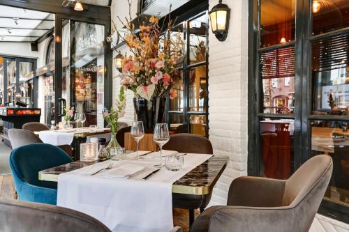 a dining room with tables and chairs and windows at Hotel Brasserie Den Engel in Baarle-Nassau