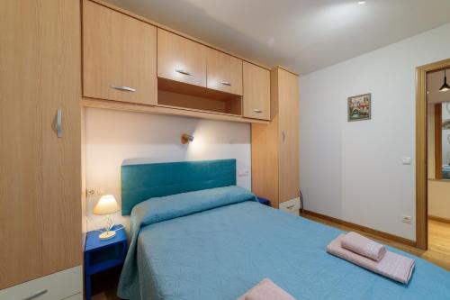 een kleine slaapkamer met een blauw bed en kasten bij Cinco de Copas in Zamora