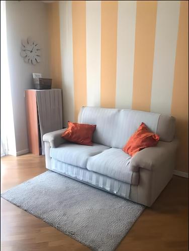 - un canapé blanc avec deux oreillers rouges dans le salon dans l'établissement Appartamento con parcheggio privato a Lucca, à Lucques