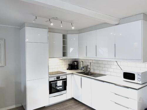 a white kitchen with white cabinets and appliances at The Apartments Company - Bislett in Oslo