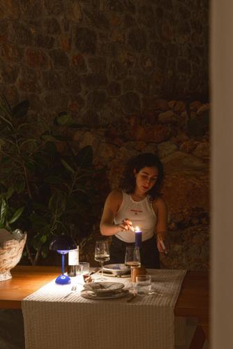 a woman standing next to a table with a candle at LASPI / PETRES in Pefkali