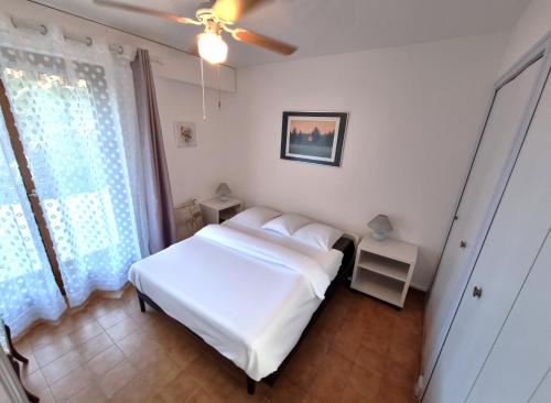 une chambre avec un lit blanc et une fenêtre dans l'établissement Acanthes - Appartement avec jardin - À 5 minutes des plages, au Lavandou