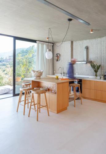 a kitchen with wooden cabinets and a table with stools at LASPI / PETRES in Pefkali