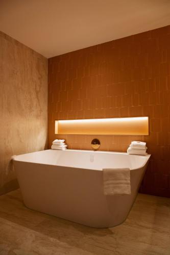 a bath tub in a bathroom with a light on the wall at Van der Valk Hotel Eindhoven-Best in Best