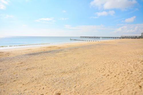 an empty beach with a pier in the distance at Stunning Victorian pub conversion apartment in Lowestoft