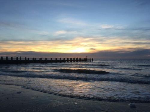 a beach with a pier and the ocean at sunset at Stunning Victorian pub conversion apartment in Lowestoft