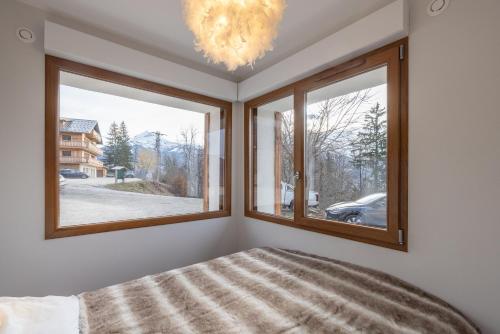 1 dormitorio con 2 ventanas y lámpara de araña en Le Pacardou, en Saint-Gervais-les-Bains