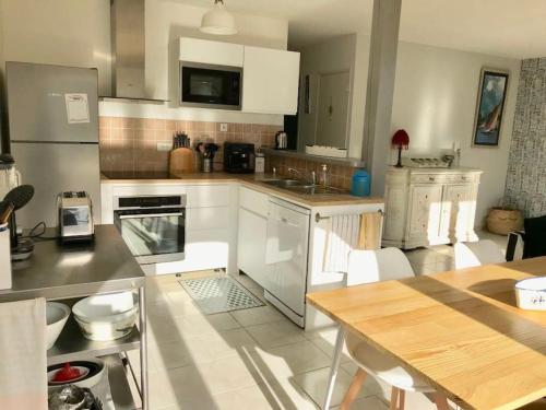 une cuisine avec des armoires blanches et une table à l'intérieur dans l'établissement Maison 6 personnes à 100m de la plage Bonne Source, à Pornichet