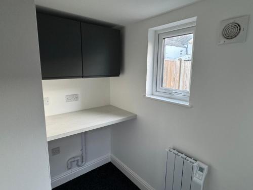 a kitchen with a counter and a window at Herne Bay 2-Bedroom House with Private Hot Tub & Garden, Walk to Seafront in Kent
