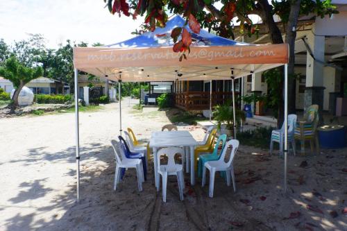 una mesa y sillas bajo una sombrilla blanca en The Beach Park Hadsan en Lapu Lapu City