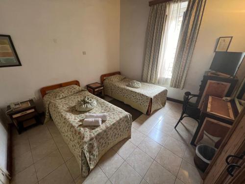 キレニアにあるNostalgia Boutique Hotel Girneのベッド2台とテーブルが備わる小さな客室です。