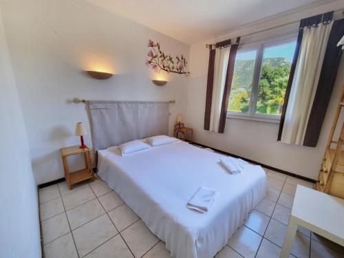 une chambre avec un lit blanc et une fenêtre dans l'établissement Les Hippocampes - T2 avec clim et parking, au Lavandou