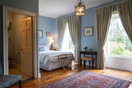 a bedroom with blue walls and a bed and a window at Kilfane Glebe House in Thomastown