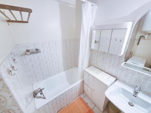 une salle de bain blanche avec une baignoire et un lavabo dans l'établissement Les Hippocampes - T2 avec clim et parking, au Lavandou