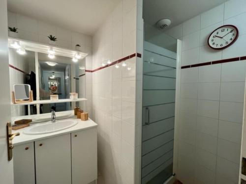La salle de bains est pourvue d'un lavabo et d'une horloge murale. dans l'établissement Appartement de charme T3 avec petit jardin et parking, à La Teste-de-Buch