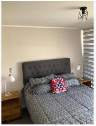 um quarto com uma cama com duas almofadas em Departamento en macul em Santiago