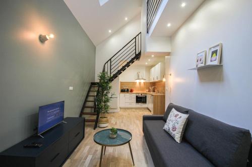 Il comprend un salon doté d'un canapé, d'une télévision et d'un escalier. dans l'établissement Lille Centre - Nice, cozy and functional ap., à Lille