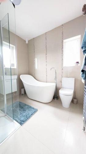 a white bathroom with a tub and a toilet at Charming Character House in Beautiful Neighborhood in Belfast