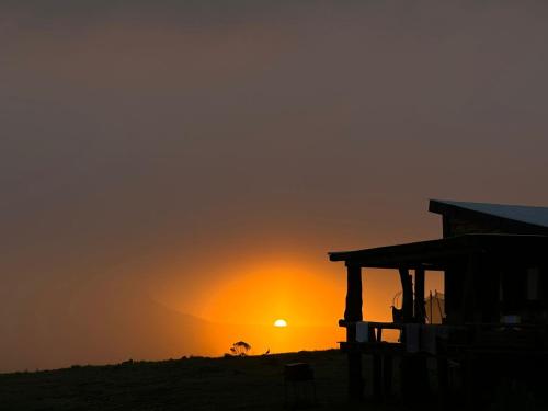una puesta de sol en la playa con un edificio y el océano en Valle de la Luna en Tandil