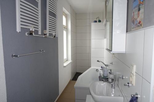 a white bathroom with a sink and a bath tub at Ferienwohnung im Logierhaus Villa Ihler in Luisenthal