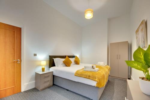 a bedroom with a bed with a yellow blanket at Lord Grey Apartments by Week2Week in Newcastle upon Tyne