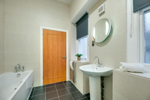 a bathroom with a tub sink and a mirror at Lord Grey Apartments by Week2Week in Newcastle upon Tyne