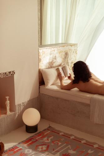 a woman laying on a bed reading a book at LASPI / PETRES in Pefkali