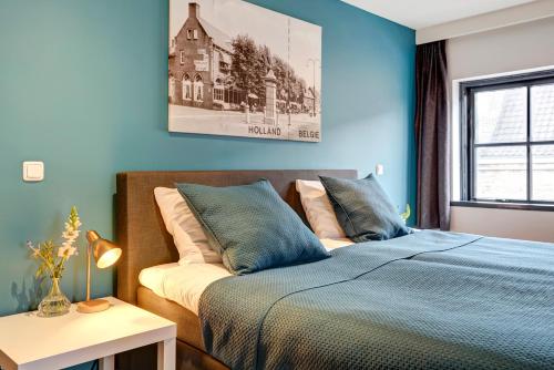 1 dormitorio con 1 cama con pared azul en Hotel Brasserie Den Engel en Baarle-Nassau