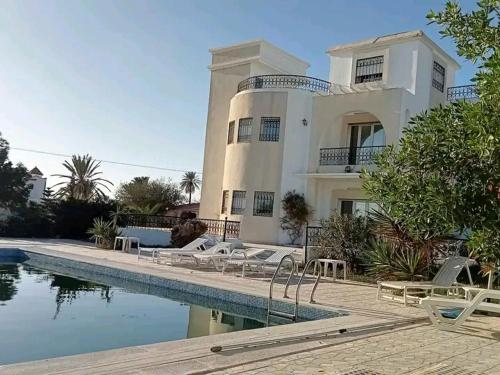 uma grande casa branca com uma piscina em frente em Villa Arkou Midoun em Midoun