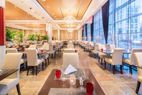 a restaurant with tables and chairs and large windows at Abba Berlin Hotel in Berlin