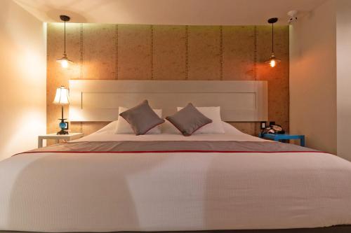 a bedroom with a large white bed with two pillows at Collection O Coraz&oacute;n Del Caf&eacute; Hotel Boutique in Comit&aacute;n de Dom&iacute;nguez