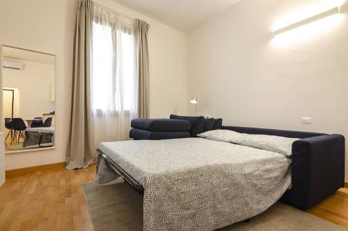 ein Schlafzimmer mit einem Bett, einem Sofa und einem Fenster in der Unterkunft Belle Arti loft, in the heart of the city in Bologna