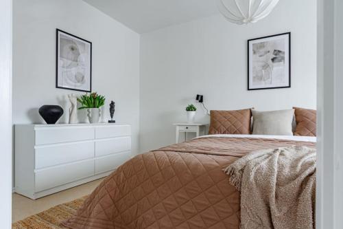a white bedroom with a bed and a dresser at Urban Oasis on Sodermalm, Sleeps Six in Stockholm