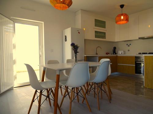 a kitchen with a table and chairs and a refrigerator at CASA DO TOMILHO by Stay in Alentejo in Vila Nova de Milfontes