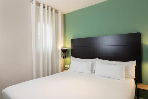 a bedroom with a white bed with a black headboard at Praktik Garden in Barcelona