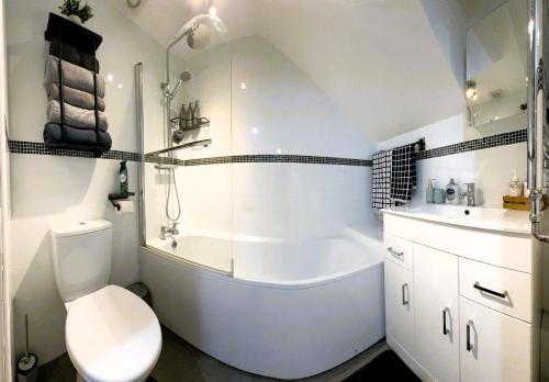a bathroom with a tub and a toilet and a sink at Large Cosy 2 bedroom Apartment in Stevenage SG1 Sleeps 5 in Stevenage