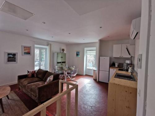 un salon avec un canapé et une cuisine dans l'établissement Soleil poudré appartement 1 chambre, pièce de vie climatisée, parking, terrasse, à Villeneuve-lès-Avignon