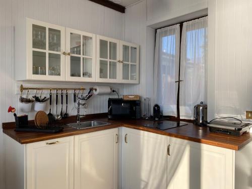 una cucina con armadi bianchi e piano di lavoro di LA PLAYA Cottage con spiaggia privata a Pettenasco