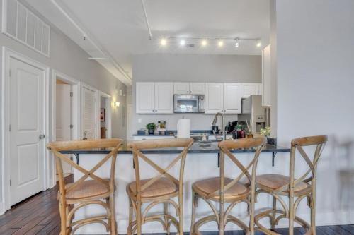 a kitchen with white cabinets and a bar with stools at Broughton Street Bungalow - Steps to Everything in Savannah