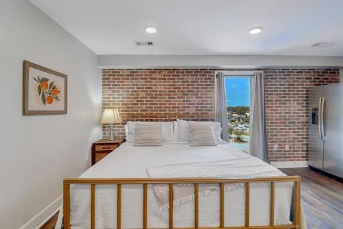 een slaapkamer met een groot bed en een bakstenen muur bij The Post Suite - above Bull & Barrel Close to GSU in Statesboro